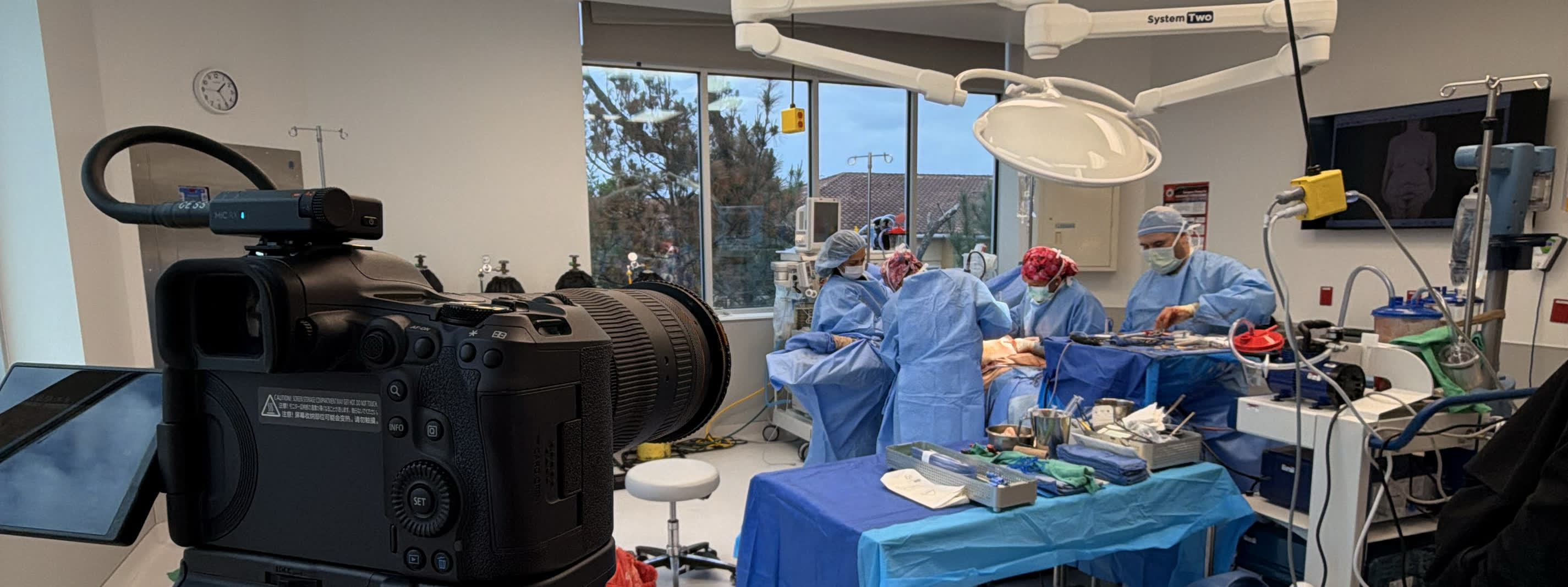 A Luma camera on a tripod filming a surgical team at work in an operating room